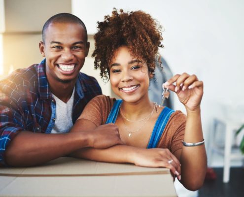 Happy couple holding new house keys while moving into their home