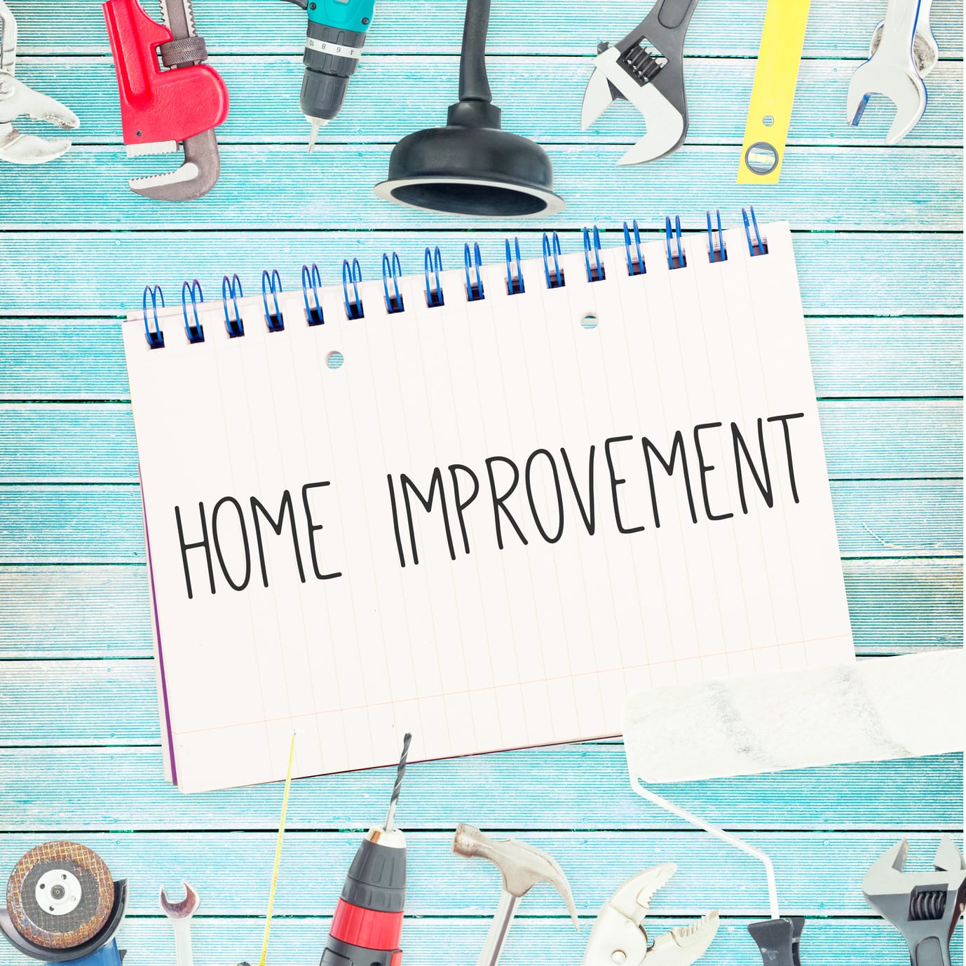 The word home improvement against tools and notepad on wooden background