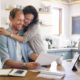 wife hugging her husband in the kitchen while the husband views homeowner insurance options
