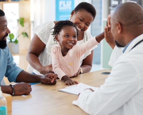 a doctor talking with a family while high fiving their daughter