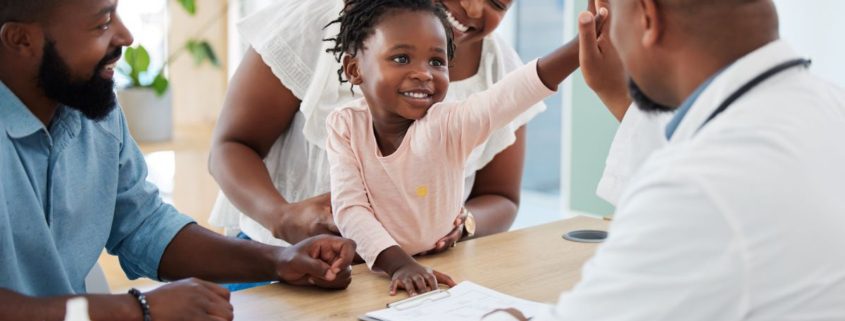 a doctor talking with a family while high fiving their daughter