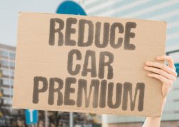 person holding a board asking how to lower your car insurance premium