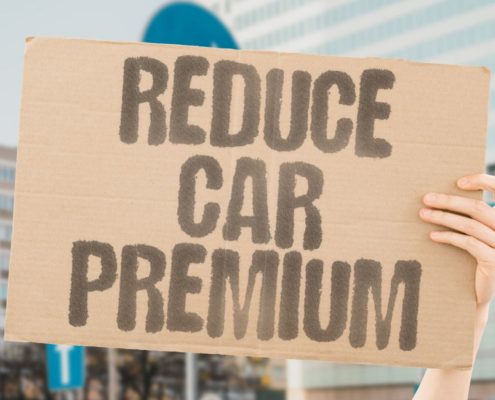 person holding a board asking how to lower your car insurance premium