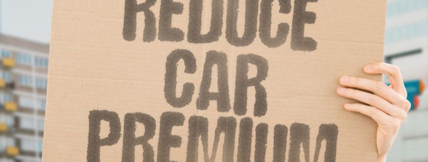 person holding a board asking how to lower your car insurance premium