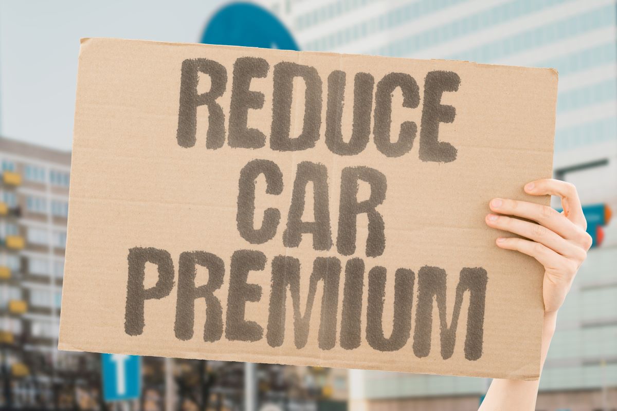 person holding a board asking how to lower your car insurance premium