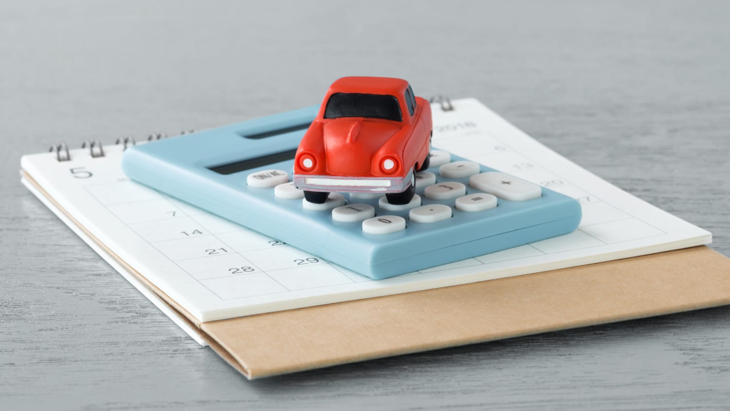 Toy car on caculator and calendar on wooden table